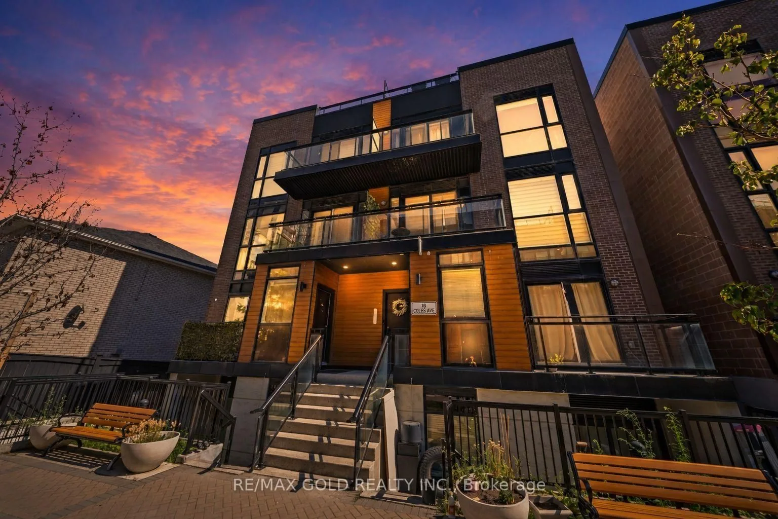Modern brick townhomes with large windows, lit up at dusk