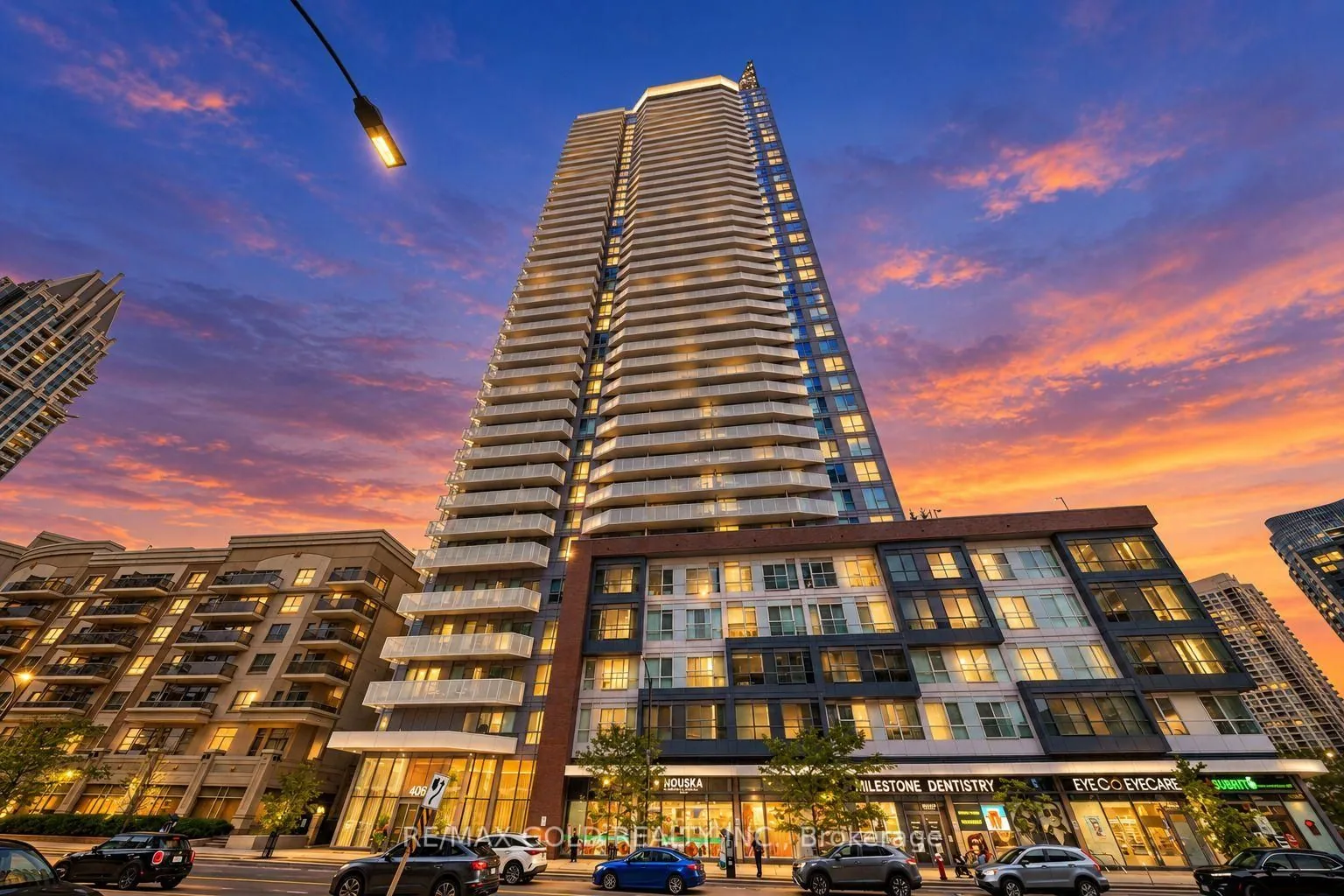 Condo tower at dusk with shops at street level