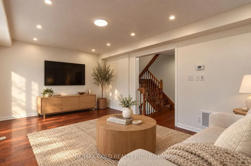 Living room with hardwood floors, a round coffee table and the staircase beyond