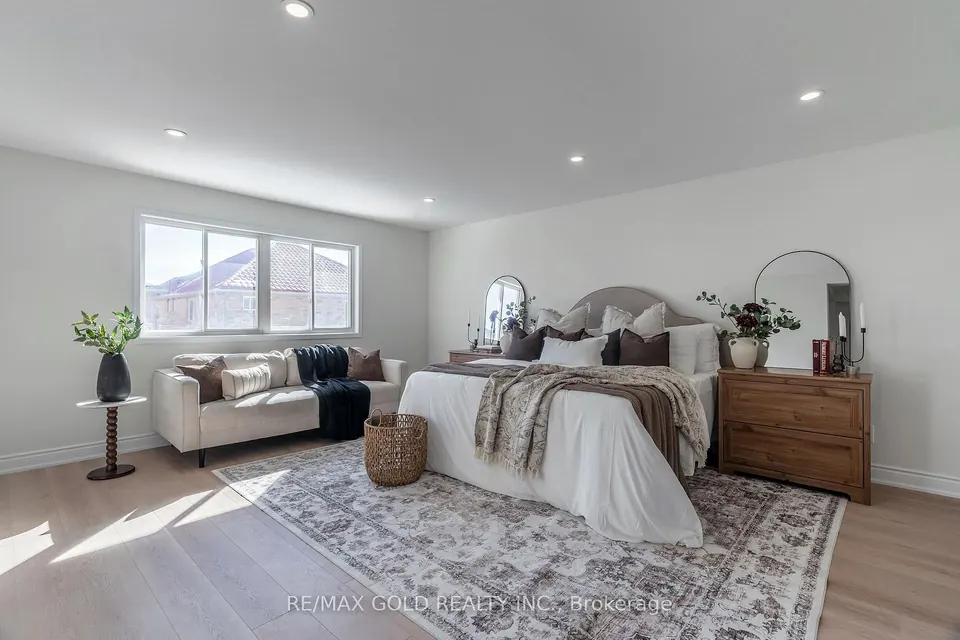 Bedroom with a large rug and a cream sofa at the foot of the bed