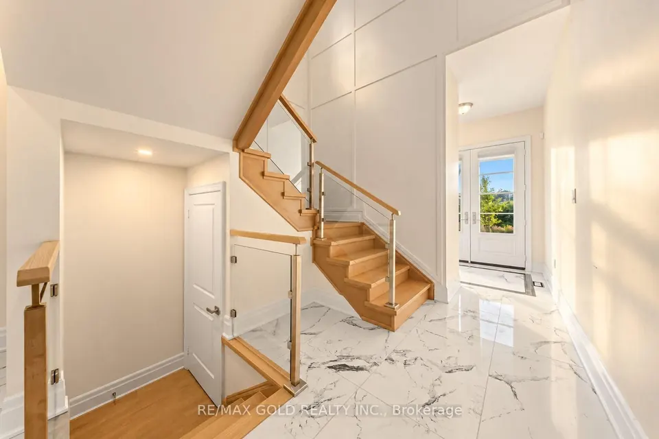 Foyer with an open oak staircase and marble floors