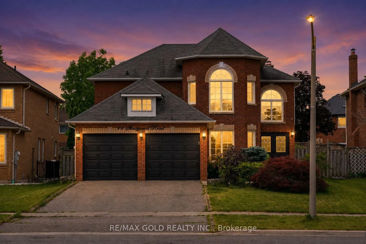 Brick home with arched windows and a double garage at dusk